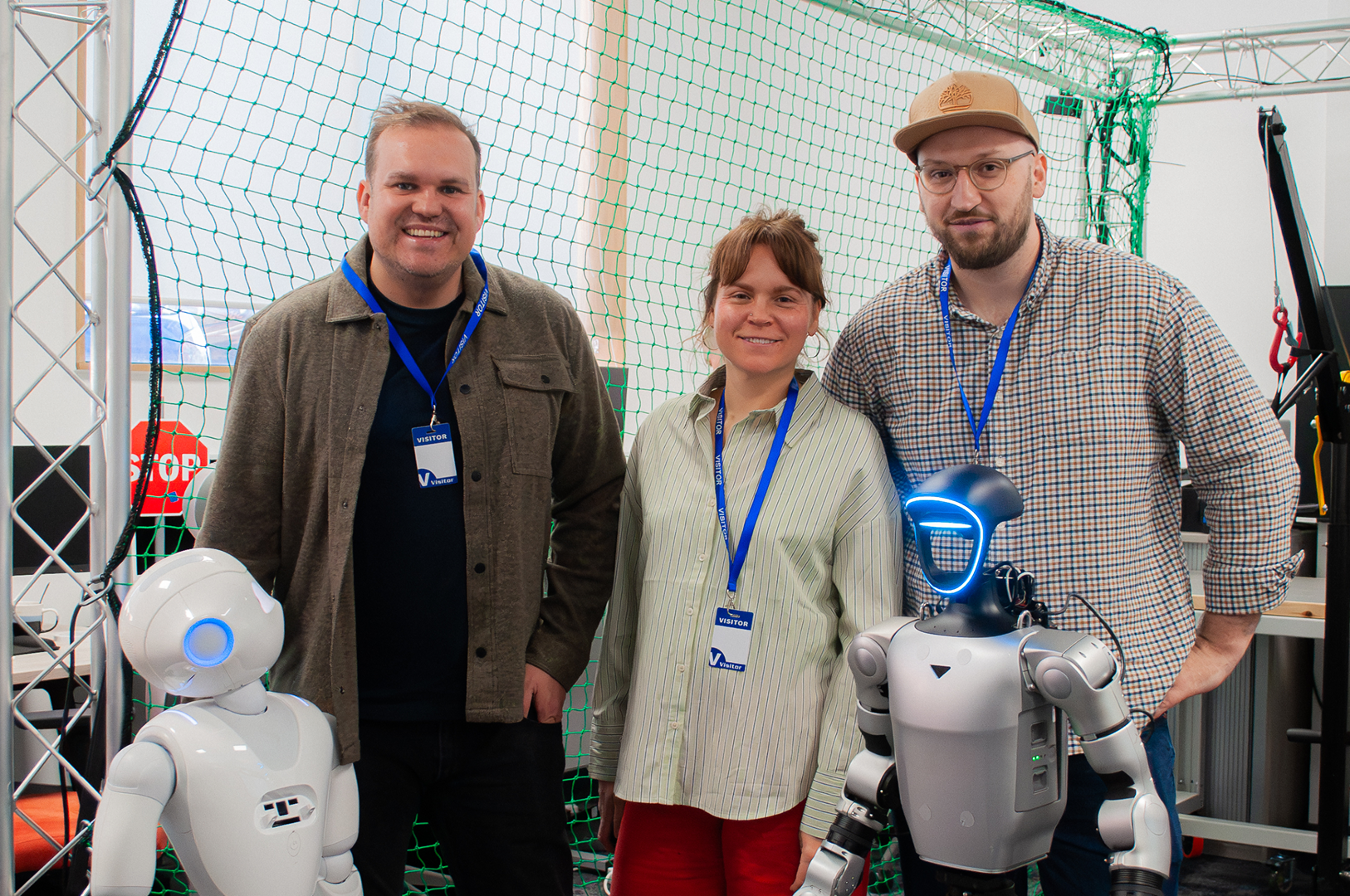 Three people from Creative Coop team standing with care robots at an exhibition